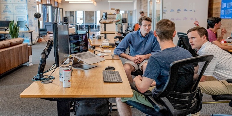 A sales team casually sitting around a desk discussing sales effectiveness.