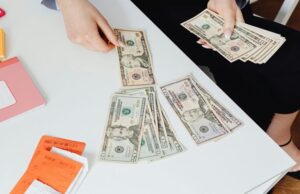 High-Angle Shot of a Person Counting Paper Money on White Table