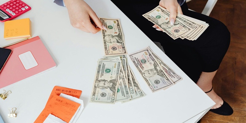 High-Angle Shot of a Person Counting Paper Money on White Table